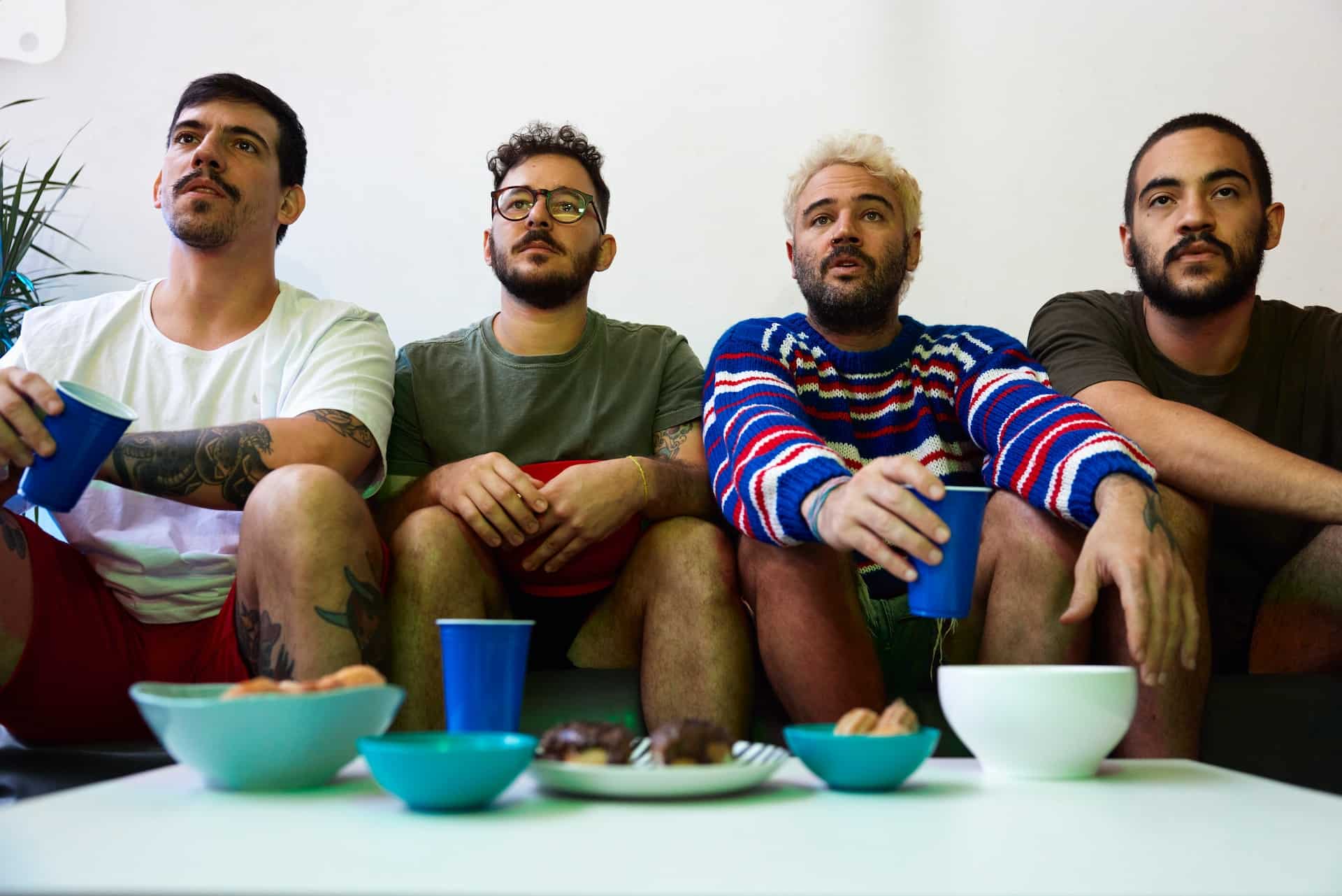 Group of male friends watching tv with snacks